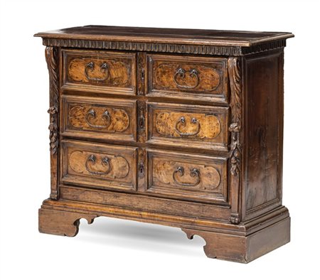 Cassettone in noce con fronte a tre cassetti, montanti intagliati a volute fogl