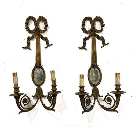 Coppia di applique a due luci in metallo dorato con attaccatura a nastro reggen