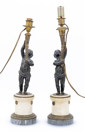 Coppia di candelieri in bronzo brunito e dorato con fusto a figura di putto reg