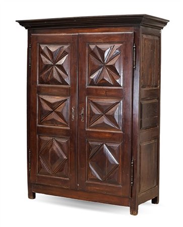 Armadio in legni vari a due ante con riserve bugnate e cappello aggettante. Sec