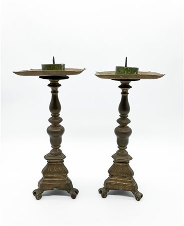Coppia di portacero in bronzo con fusto tornito su base tripode, secolo XVIII.