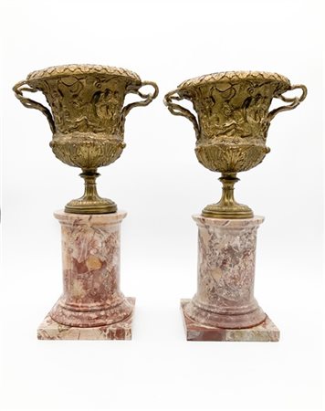 Coppia di vasi in metallo dorato decorato a giochi di putti con doppia ansa a t