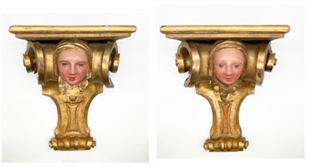 Coppia di mensole in legno intagliato, dipinto e dorato centrate da volti mulie