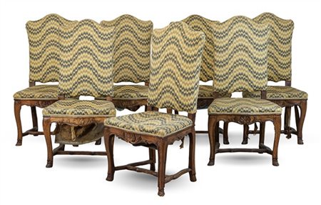 Gruppo di sette sedie di forma mossa in noce intagliato con gambe terminanti a