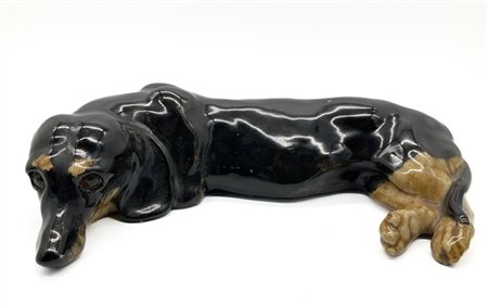 Manifattura inglese, secolo XX. Figura di cane bassotto in ceramica policroma.