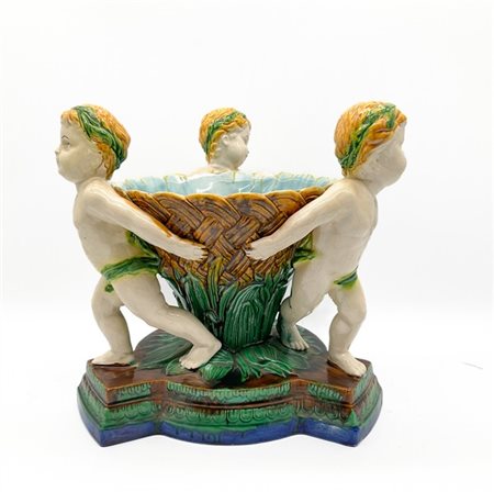 Centrotavola a cesto retto da tre putti in ceramica policroma e base sagomata n