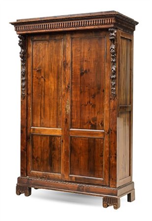 Armadio in legni vari a due ante pannellate, montanti con fregi a mascheroni e