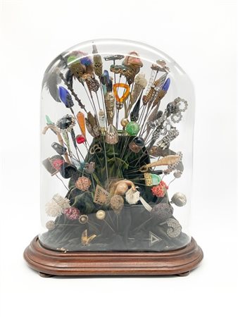 Composizione con spilloni di varie forme e materiali entro campana in vetro su