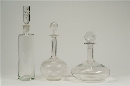 Lotto composto da un decanter in vetro trasparente Lalique France e due bottiglie una con tappo cilindrico e l'altra con alto collo scanalato e tappo a disco