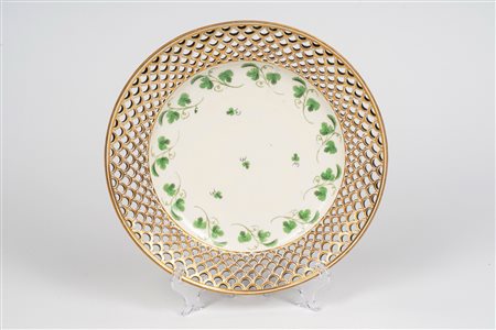 Piatto in porcellana a bordo dorato e traforato e decoro a foglie. Vienna, Secolo XIX