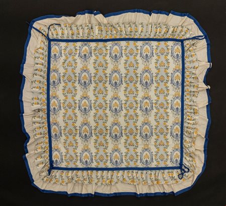 Tovaglia in cotone decorata nei toni del blu dell'azzurro e del giallo a medaglioni e fiori, bordo a balze con nastro azzuro, tessuto Güell Lamadrid