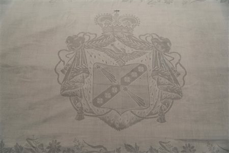 Importante tovaglia in lino decorata con quattro blasoni centrali e motivi floreali lungo il bordo