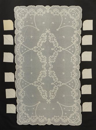 Tovaglia di forma rettangolare in cotone a pelle d'uovo a bordo mosso ricamata con due medaglioni floreali centrali e con ghirlande di fiori lungo il bordo, con dodici tovaglioli 