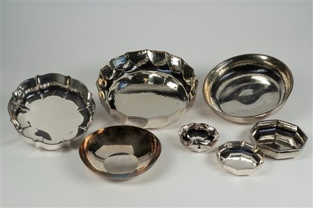 Lotto composto da sette centrotavola in metallo argentato di forme e misure differenti più un vaso e una brocca con manico in legno ebanizzato