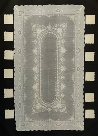 Tovaglia rettangolare in cotone con medaglione centrale di forma ovale decorata a fiori e rose, bordura mossa con riserve a fiori con 12 tovaglioli