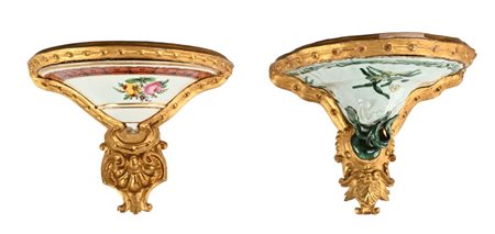 Due mensole a goccia in legno dorato, maiolica e porcellana dalle simili...