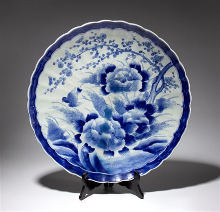  
Grande piatto in porcellana dipinta con peonie fioriti. rami di pruno ed uccellino racchiusi in un bordo blu scuro. Giappone, fine XIX-XX secolo 
 Diametro cm 48