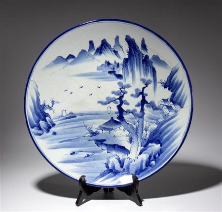  
Grande piatto in porcellana bianca e blu in stile Imari raffigurante un paesaggio naturalistico. Giappone, fine XIX-XX secolo. 
 Diametro cm 46