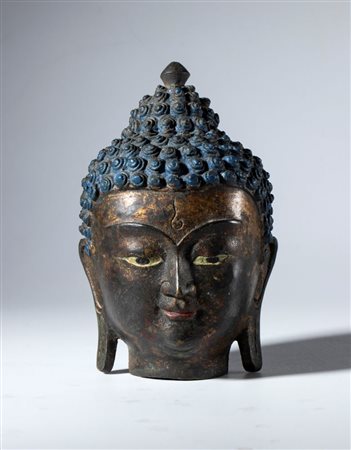  
Testa di Buddha in lega di rame parzialmente dipinto. Area Himalayana, XIX secolo 
 Complessivamente mm 126.5 x 80.5 x 80 ca.