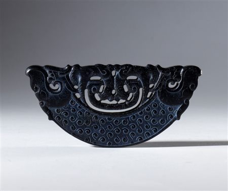  
Mezzo disco ornamentale in giada scura Hotan incisa e traforata. Decorato con motivi a spirale e figure di animali stilizzati alle estremità. Cina, dinastia Qing (1644-1912), XVIII secolo 
 Complessivo mm 77 x 37.3 x 7
