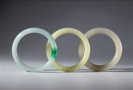  
Lotto di tre bracciali ornamentali in giada chiara e giada verda. Cina, dinastia Qing (1644-1911), XIX secolo 
 Diametro interno di ognuno mm 57