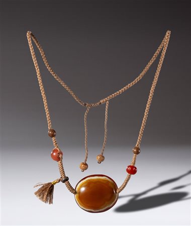  
Collana con perla piatta Lukmik in agata zonata bianco arancio, con perle in corniola, legno, osso e argento. Tibet, XVIII secolo 
 Lunghezza complessiva cm 28 ca.
