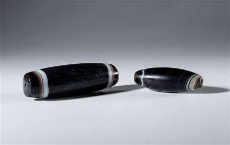  
Lotto di due perle tubolari in agata zonata bianco nera. Tibet, XIX secolo 
  mm 57.4 x 20 / 80.8 x 25.4