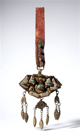  
Borsello per acciarino in pelle decorato con placche metalliche sbalzate, incise e parzialmente dorate. Coralli (Corallium rubrum) e turchesi applicati in castoni. Tibet, XIX-XX Secolo 
 Lunghezza complessiva cm 35 ca.