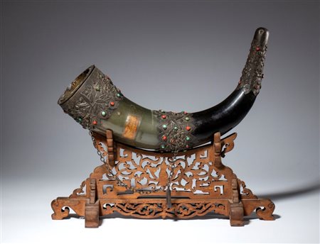  
Grande corno bovino con applicazioni in metallo sbalzato ed inciso con incastonati turchesi e coralli. Base in legno traforato. Cina, XIX secolo 
 Lunghezza del corno cm 35 ca. 