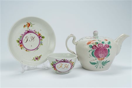 Lotto composto da una tazzina con piattino in porcellana decorata in policromia con monogramma in un cartiglio color porpora ed una teiera con decoro policromo a fiori. Germania, Wallendorf, 1770-1790 circa