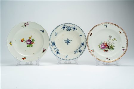 Tre piatti in porcellana uno con decoro bianco-blu a motivi floreali, uno al mazzetto e fiori sparsi, l'altro a bordo mosso e dorato con scena galante tra fiori e insetti. Vienna, fine secolo XIX