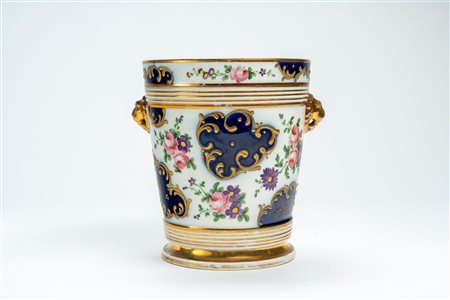 Porta vaso biansato in porcellana decorata a bouquet di fiori e riserve blu con rocaille dorate a rilievo. Probabilmente Francia, secolo XIX