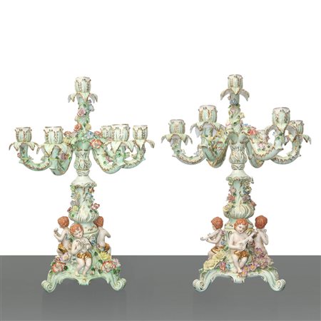 Coppia di candelabri a 7 luci in porcellana tedesca policroma con putti suonatori e tralci di fiori rampicanti, 20° secolo