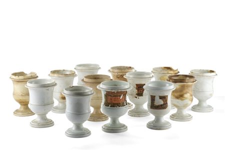 Tredici vasi da farmacia in ceramica bianca, alcuni con etichette stampate. Ini