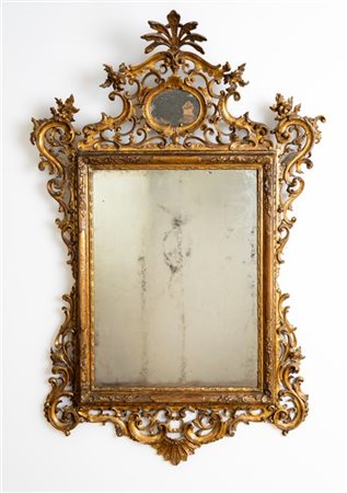 Specchiera in legno intagliato e dorato con fregi a volute traforate e motivi f