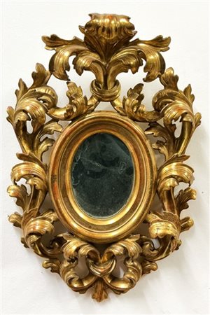 Cornice di forma ovale in legno intagliato, traforato e dorato a volute contrap