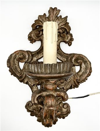 Antica applique a torciera in legno intagliato, argentato e traforato a volute.