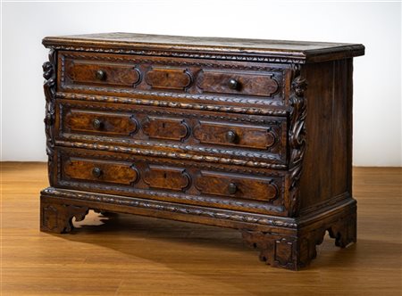 Cassettone in noce con fronte a tre cassetti con bordure decorate a foglie e bu