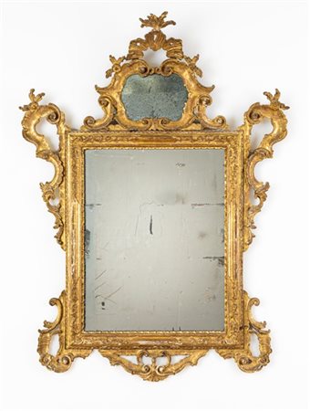 Specchiera in legno intagliato e dorato a volute e motivi rocaille con cimasa c