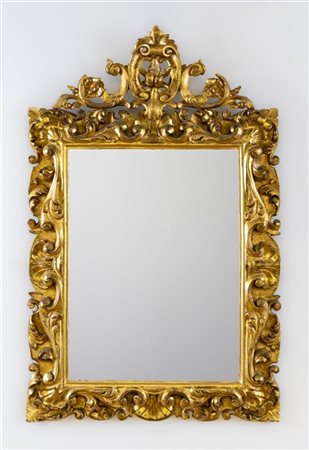 Specchiera con cornice in legno intagliato e dorato a volute fogliate. Secolo X