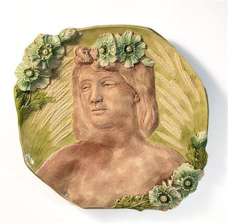 Placca in ceramica sagomata con figura e fiori a rilievo. Italia, s20. Firma im