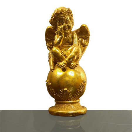 Putto dorato accovacciato su un globo