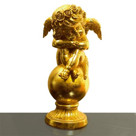 Putto dormiente dorato accovacciato su un globo