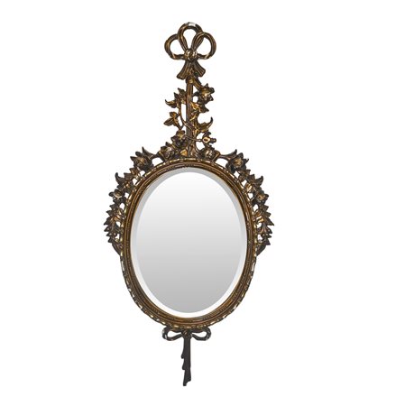 Specchiera ovale entro cornice in legno dorato con decori floreali e fiocchi pendenti alla sommità e alla base, 20° secolo