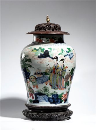  
Potiche in porcellana wucai decorata con una scena raffigurante dame e bambini all'interno di un giardino con coperchio in legno e bronzo. Cina, dinastia Qing, periodo Kangxi 
 Altezza cm 33; altezza coperchio cm 9,3 