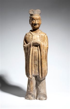  
Figura in ceramica raffigurante un funzionario di corte, stante con le mani raccolte nelle ampie maniche e copricapo da ufficiale. Cina, dinastia Tang, VIII secolo 
 Altezza cm 45