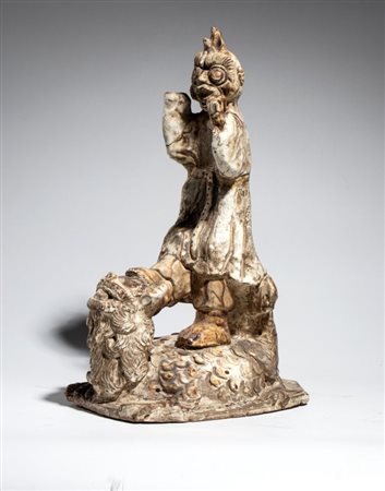  
Figura di demone in ceramica a smalto bianco in abiti tradizionali ed espressione terrifica poggiante su una creatura mitologica. Asia del Sud Est, XIX secolo 
 Altezza cm 38,3; larghezza cm 22,5