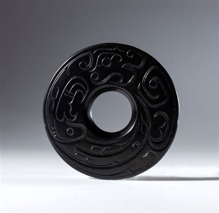  
Disco BI in giada nera Hotan con decoro inciso raffigurante un drago schematizzato, Cina, dinastia Qing (1644-1912), XIX secolo 
 Diametro esterno cm 7,5; spessore cm 0,47