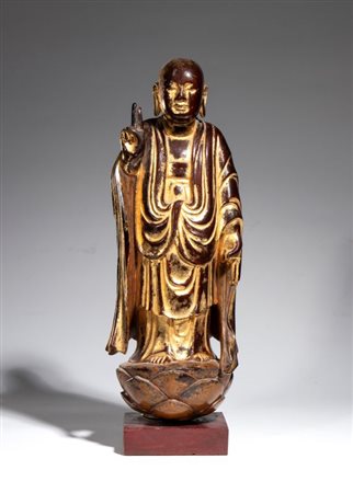  
Figura in legno dorato raffigurante un monaco buddista (Arhat/Luohan) in piedi su un loto. Cina, fine dinastia Ming XVII secolo 
 Con base: Altezza cm 43; larghezza cm 15; profondità cm 10,5