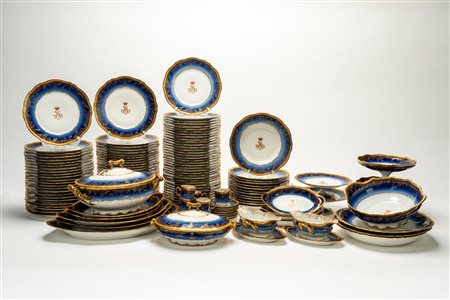 Servizio da tavola in porcellana bianca con fascia blu cobalto sfumata, decori in oro a rilievo lungo bordo mosso e monogramma coronato al centro. Théodore Haviland, Limoges, Francia. "Mousseline", inizio secolo XX